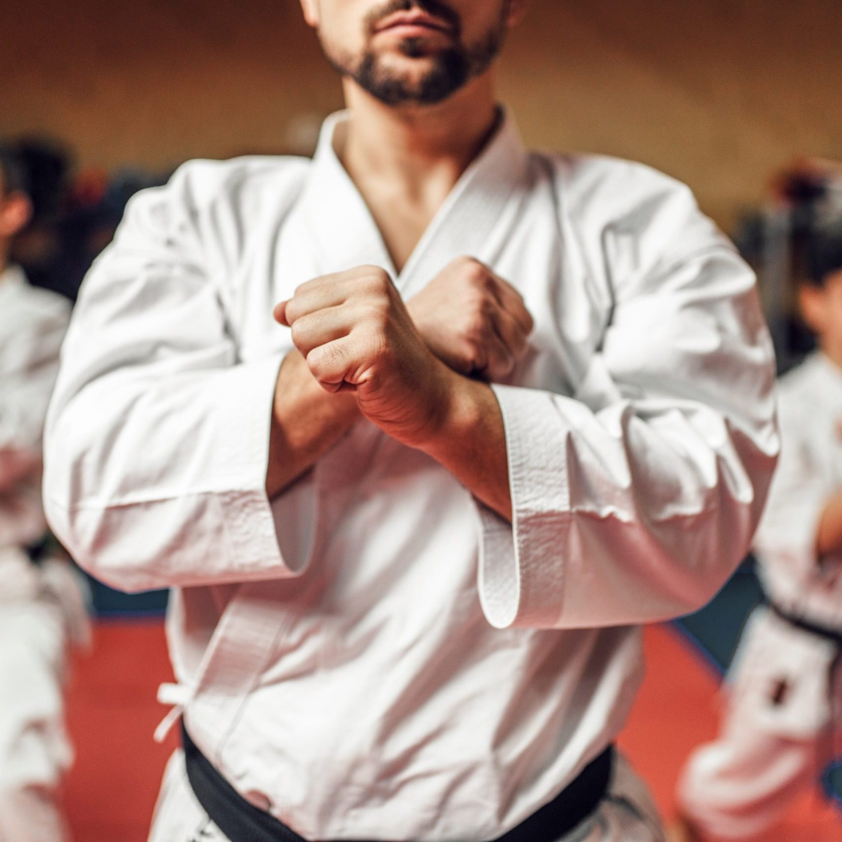 Martial arts karate fighters, master and his disciples in white kimono and black belts hone their skills, fight training in action, workout in gym